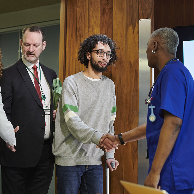 A photo of a group of people all shaking hands. There appears to be a business person or social worker with a client and a healthcare professional.