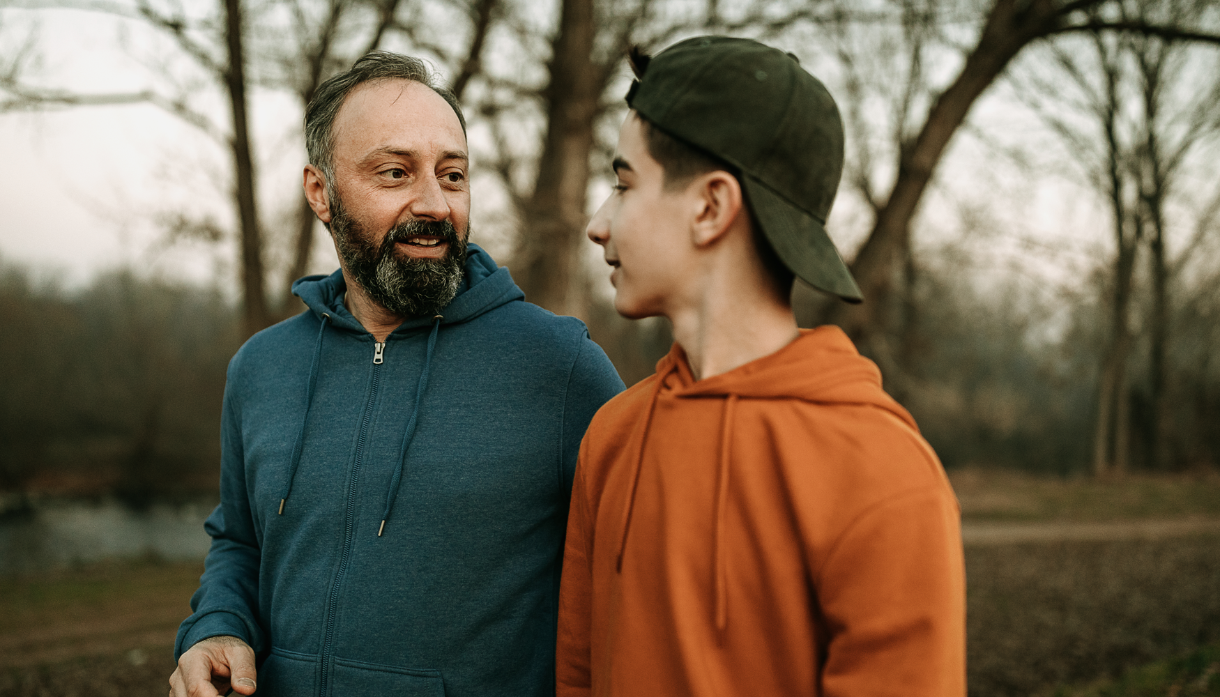A photo of a man talking to a young teenage boy. He could be either a counsellor talking to one of his clients or a dad speaking to his son.