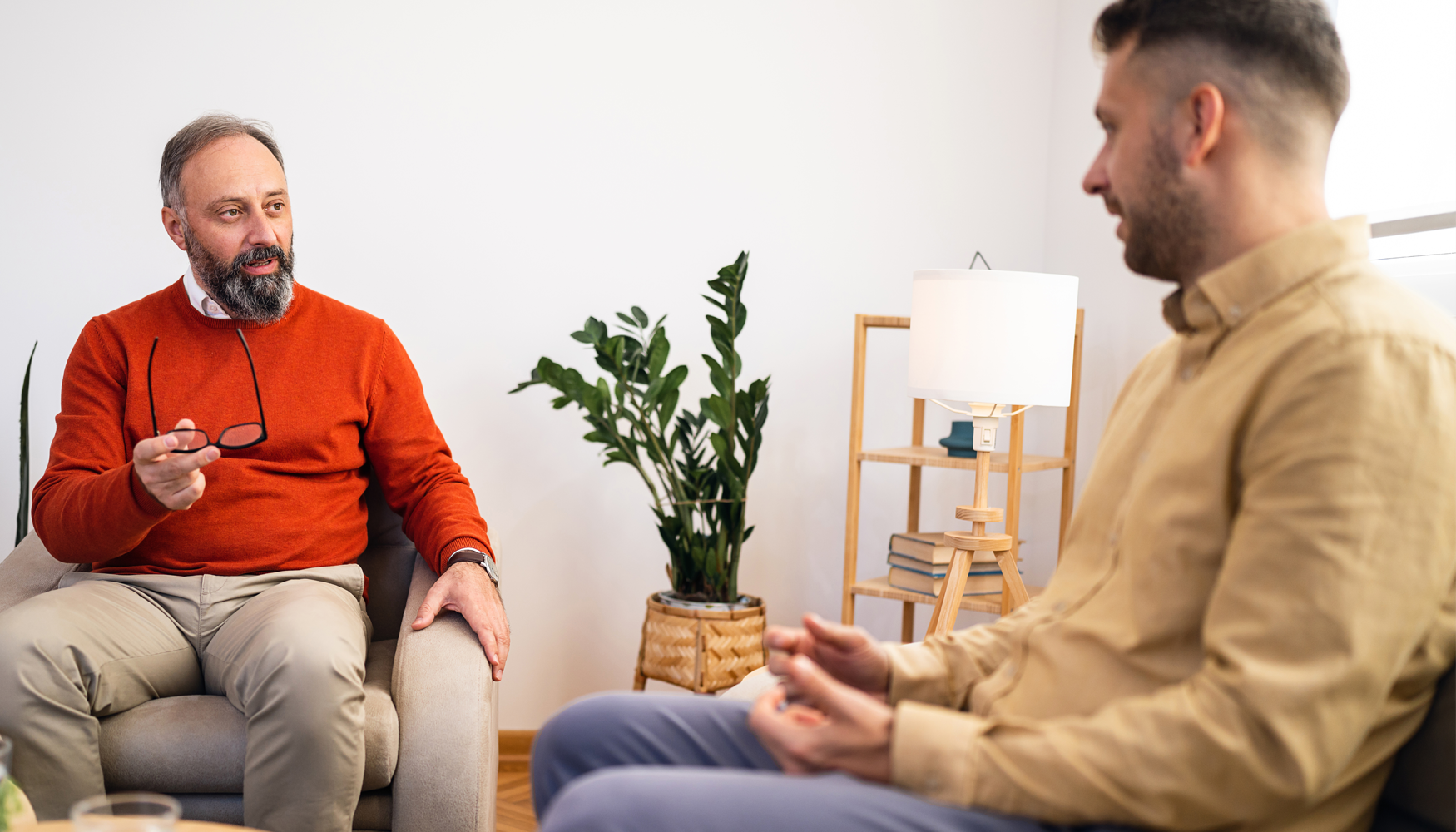 A photo of two men engaged in a conversation with each other. One of the men appears to be a counsellor providing advice to the other.